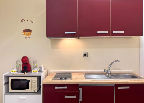 Cocina moderna en apartamento de Baiona con muebles burdeos, microondas, fregadero, estufa y cafetera en la encimera