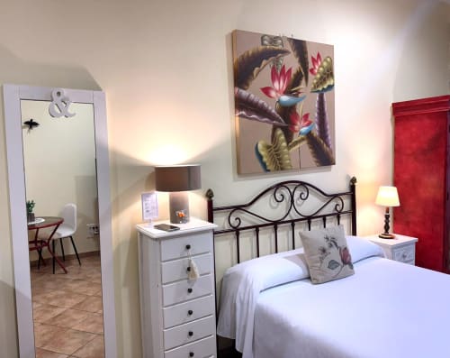 Apartamento Vermello en Baiona con cama doble, cabecero de hierro forjado, mesita blanca y cuadro de pájaros en la pared