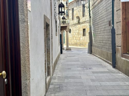 Estrecho callejón empedrado en el centro histórico de Baiona con edificios de piedra y farolas tradicionales