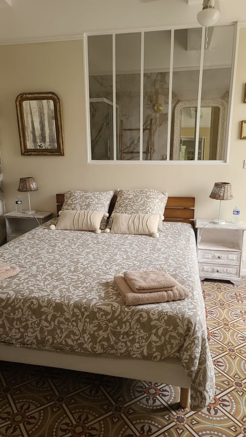 Chambre élégante au N°9 B&B à Argeliers avec literie à motifs, coussins décoratifs, lampes de chevet et vue sur le jardin