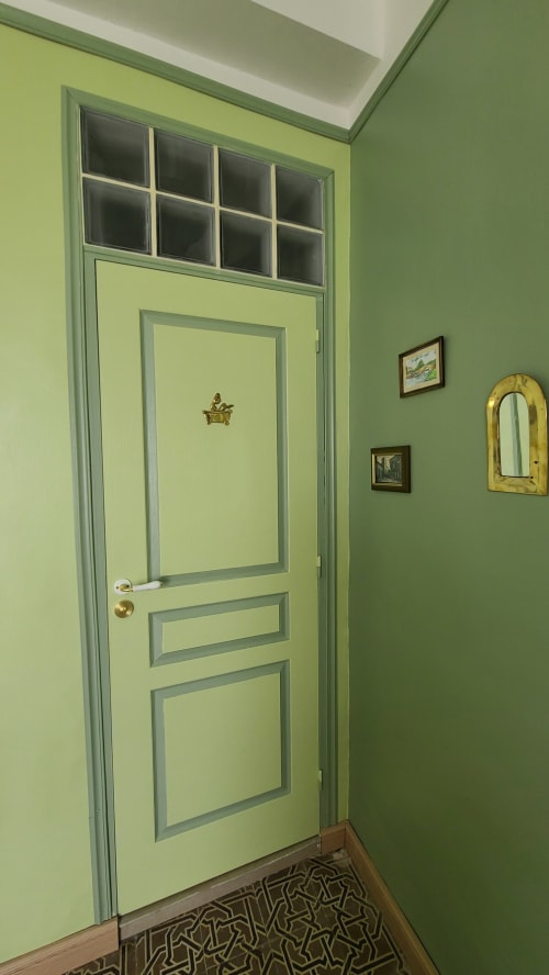 Couloir avec porte jaune pâle et murs verts au gîte Le N°9 à Argeliers, France