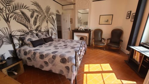 Chambre Narbonne au gîte Le N°9 à Argeliers, avec parure motifs, carrelage terre cuite et papier peint tropical.