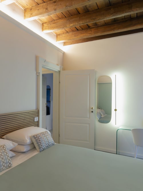 Modern Milan boutique hotel room with wooden beam ceiling, bed with striped headboard, and contemporary decor