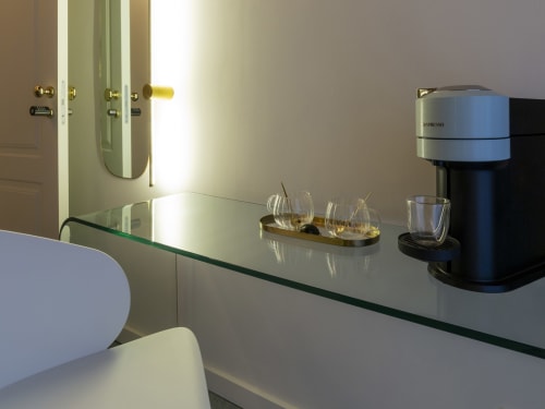 Modern hotel room detail: glass countertop with Nespresso machine, glasses, and brass accessories in Milano boutique room