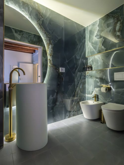 Modern Milano bathroom with marble walls, floating gold shelves, white fixtures, and sliding glass doors at Moon River room,