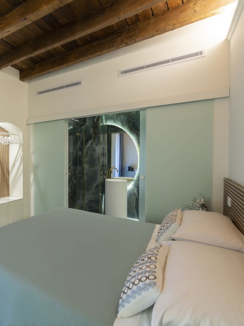 Modern bedroom at YOUnique Boutique Rooms Milano with frosted glass sliding doors to ensuite bathroom, exposed wooden beams,