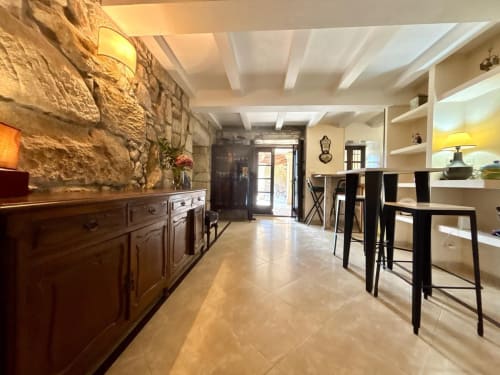 Interior moderno de villa en Holibai Baiona con pared de piedra, muebles de madera, barra con asientos negros y comedor abierto