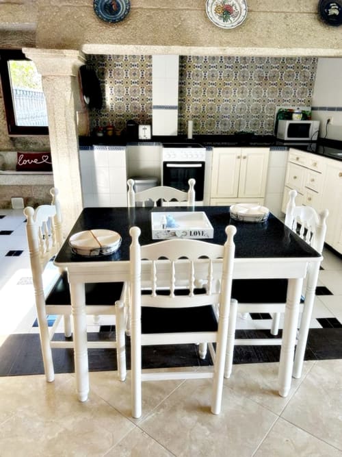 Comedor con mesa negra y blancas sillas en cocina de villa, Baiona