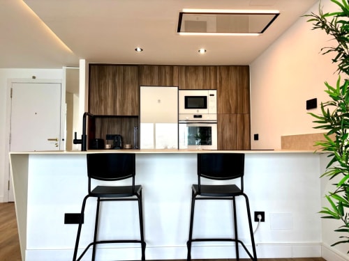 Cocina moderna con barra desayunadora y taburetes negros en el apartamento Meiga do Mar, Baiona