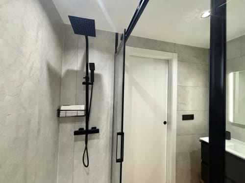 Baño moderno con ducha de efecto lluvia y accesorios en negro en el apartamento Meiga do Mar, Baiona