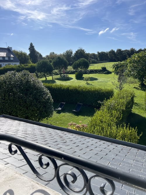 Vue pittoresque du jardin aux Gîtes De L'odet à Clohars-Fouesnant avec haies taillées, chaises longues et cadre champêtre