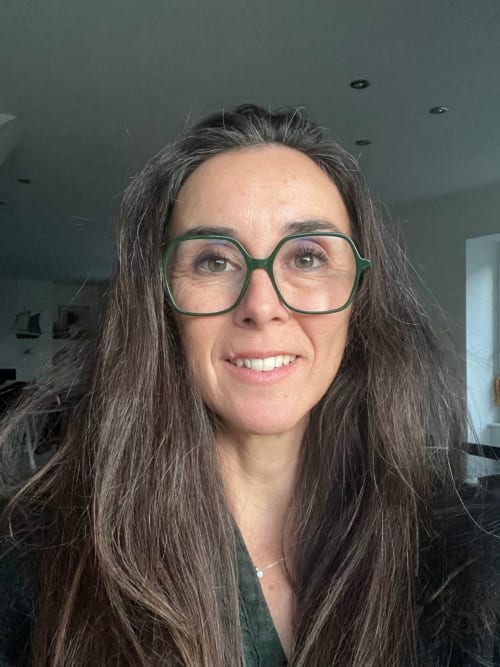 Femme souriante aux longs cheveux noirs et lunettes vertes aux Gîtes de L'odet, Clohars-Fouesnant