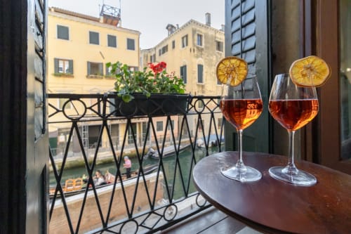 Due cocktail aperitivi con fette d'arancia su un balcone veneziano affacciato sul Canal Grande e gli storici edifici palazzo