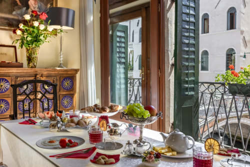 Colazione elegante al Palazzo San Firmino di Venezia con frutta fresca, pasticcini e vista sul canale dalla terrazza.