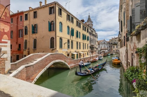 Canale veneziano con gondole, ponte in mattoni ad arco e storici edifici colorati al Palazzo San Firmino a Venezia