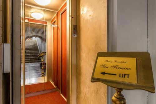 Ingresso dell'ascensore a Palazzo San Firmino Residenza D'Epoca con cartello direzionale a Venezia, Italia