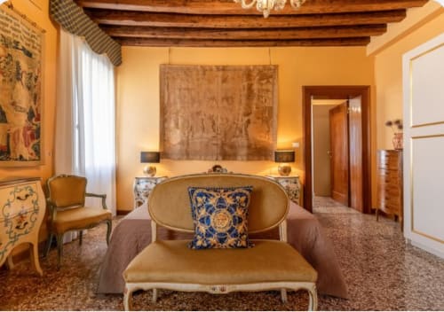 Elegante camera veneziana a Palazzo San Firmino con pareti dorate, travi a vista e arredi ornamentali