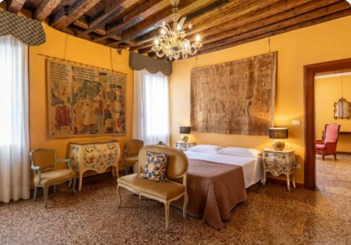 Camera da letto lussuosa e storica presso il Palazzo San Firmino di Venezia con pareti gialle, lampadario ornato e arredi classici