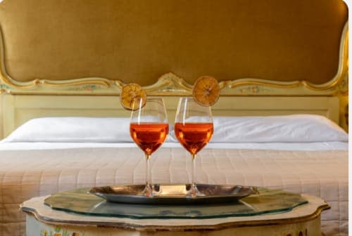 Camera da letto romantica al Palazzo San Firmino Venezia con bicchieri di vino e agrumi secchi sulla testata ornamentale