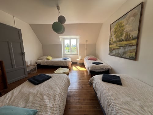 Chambre spacieuse et lumineuse aux Gîtes De L'odet avec lits multiples, parquet, vue sur le jardin et équipements modernes