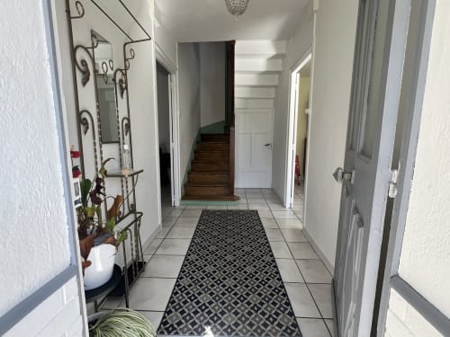 Entrée lumineuse du gîte Les Gîtes De L'odet avec sol carrelé, tapis à motifs et escalier