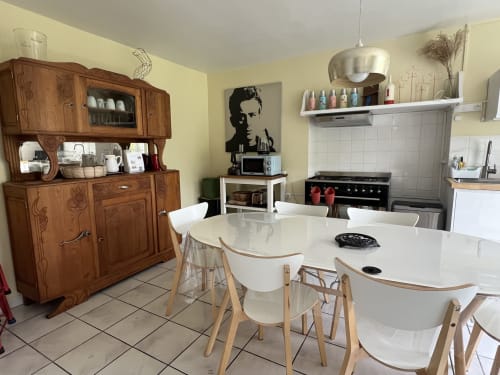 Cuisine-salle à manger de charme aux Gîtes De L'odet : tables blanches, chaises en bois et armoire vintage.