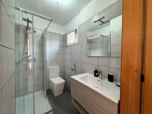 Moderno bagno nell'appartamento di Sormano con doccia aperta, doppio lavabo, WC e mobile con specchio
