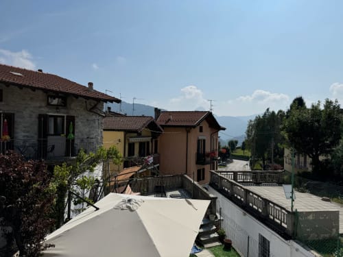 Vista della terrazza dell'Apartment Sormano 2 della Collezione THE V con panorama montano e edifici vicini, Sormano, Italia