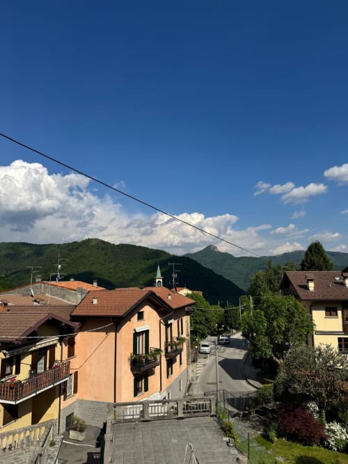 Appartamento nel villaggio di Sormano con vista montagna, edifici con tetto in terracotta, colline verdi e cielo blu