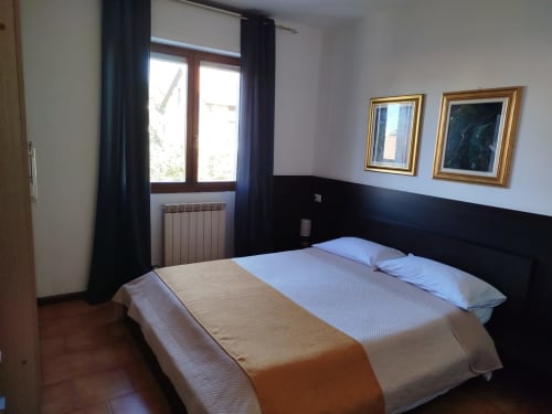 Modern bedroom in Carducci Apartment at THE V Collection Turate, with double bed, black headboard, garden view window, and