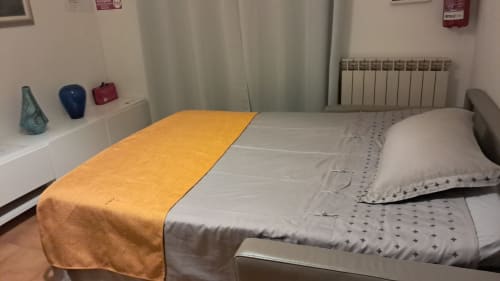 Carducci Apartment bedroom at THE V Collection Turate with yellow throw blanket, white bedding, pillow, radiator, and shelf