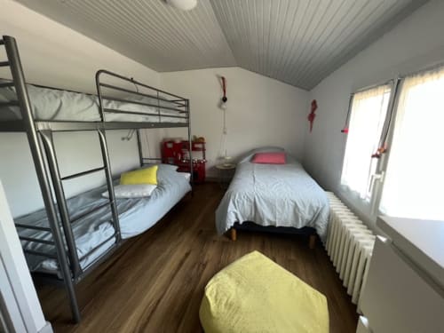 Chambre de gîte aux Gîtes De L'odet avec lit superposé, lit simple, parquet et fenêtres vue jardin
