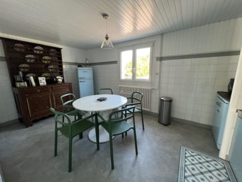 Cuisine et salle à manger du gîte avec table ronde, chaises vertes, mobilier vintage et appareils modernes