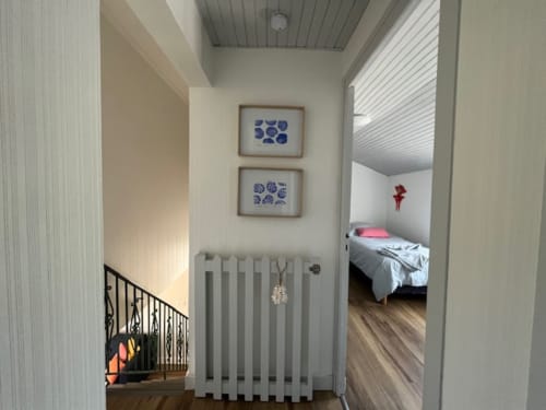 Entrée du couloir des Gîtes De L'odet avec œuvre bleue et radiateur, accès à la chambre