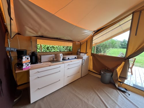 Intérieur de glamping aux Gîtes De L'odet avec cuisine équipée, placards blancs, électroménagers et vue sur le jardin