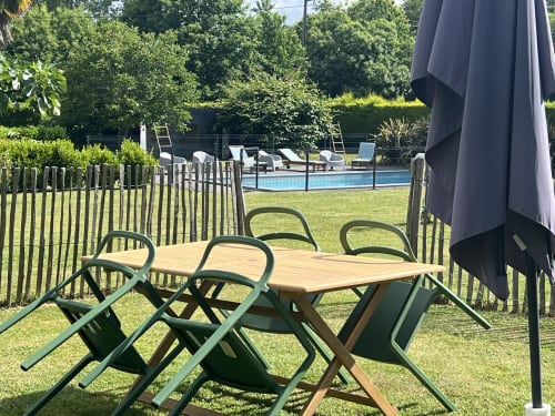 Terrasse de restaurant des Gîtes De L'odet avec table, chaises, parasol et vue sur la piscine à Clohars-Fouesnant