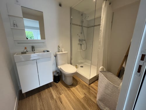 Salle de bains moderne aux Gîtes De L'odet avec vasque blanche, toilettes et douche à l'italienne avec paroi vitrée