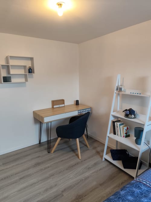 Espace de travail moderne à l'hôtel Accolade à Châteaudun avec bureau en bois, chaise noire et étagères blanches