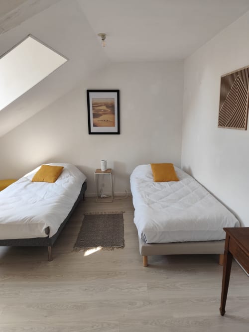 Chambre twin à l'appartement Accolade à Châteaudun avec literie blanche, coussins moutarde et puits de lumière