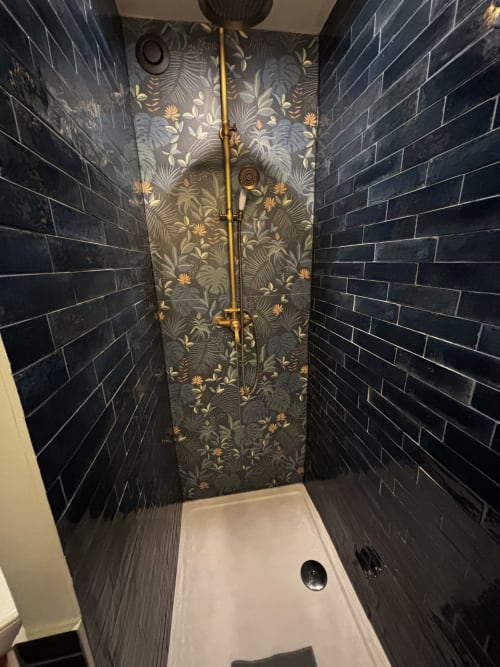 Élégante douche avec carrelage noir, panneau central à motifs et accessoires en laiton à Le Prieuré Du Preux