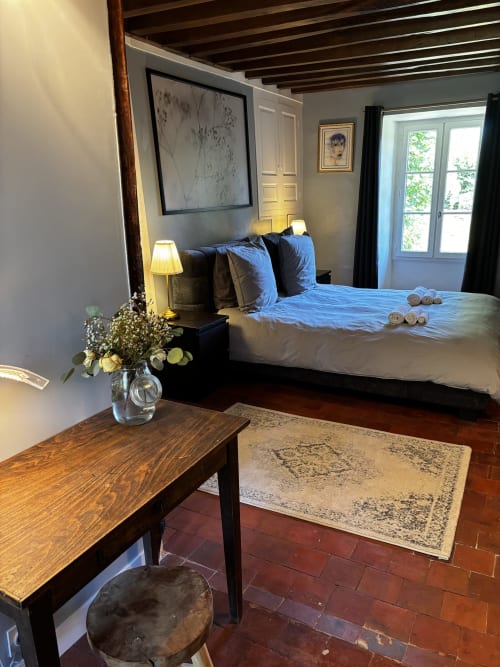Chambre élégante du Prieuré Du Preux avec literie bleue, bureau en bois fleuri et vue sur le jardin par portes-fenêtres