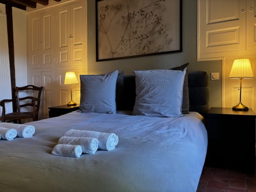 Chambre élégante au Prieuré Du Preux avec coussins bleus, serviettes roulées et éclairage chaleureux à Sépeaux Saint Romain