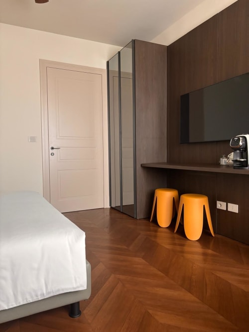 Camera moderna del B&B Delta Majestic a Pordenone con rivestimenti in legno scuro, sgabelli arancioni e pavimentazione a spina di pesce