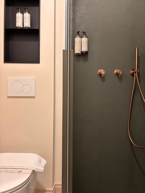Moderno bagno del B&B Delta Majestic di Pordenone con dispenser doppi, finiture in rame e design minimalista