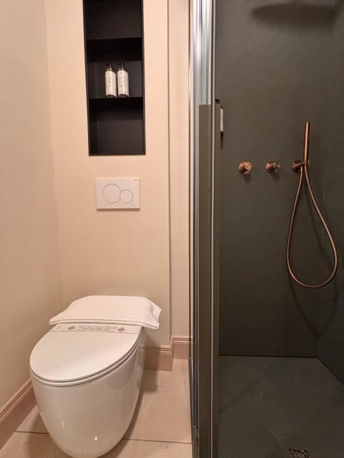Bagno moderno al B&B Delta Majestic con vaso riscaldato, ripiani neri, rubinetteria rame e vista montagna