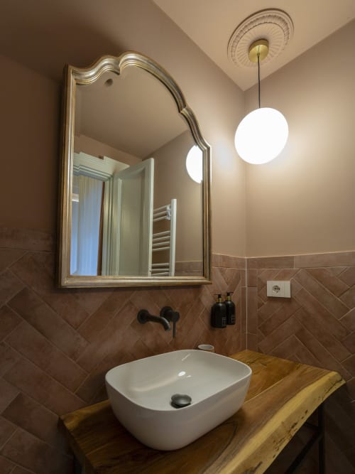 Modern bathroom sink with mirror at YOUnique Boutique Rooms Milano, featuring white vessel sink and pendant lighting