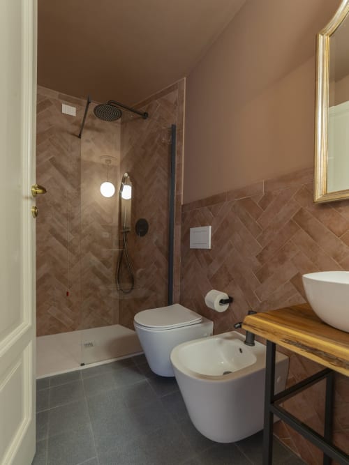 Modern bathroom with herringbone tile, walk-in shower, white toilet and sink at YOUnique Boutique Rooms Milano