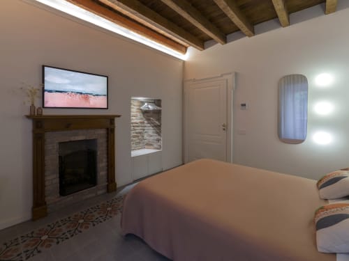 Modern bedroom at YOUnique Boutique Rooms Milano with fireplace, flat-screen TV, exposed beams, and contemporary furnishings