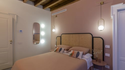 Modern bedroom at YOUnique Boutique Rooms Milano with rattan headboard, pendant lights, mirrored vanity, and city views
