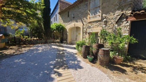 Cour charmante de la chambre d’hôte Le N°9 à Argeliers, avec bâtiments en pierre, tonneaux et ses agrumes.